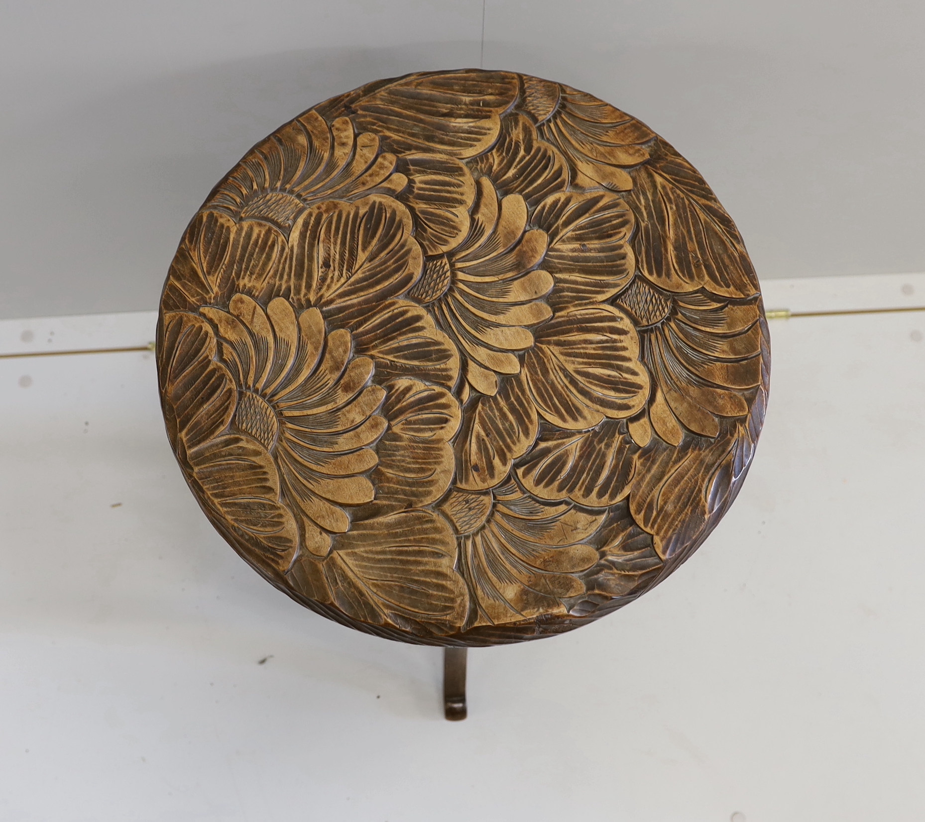 An early 20th century Liberty style carved two tier occasional table, diameter 44cm, height 61cm